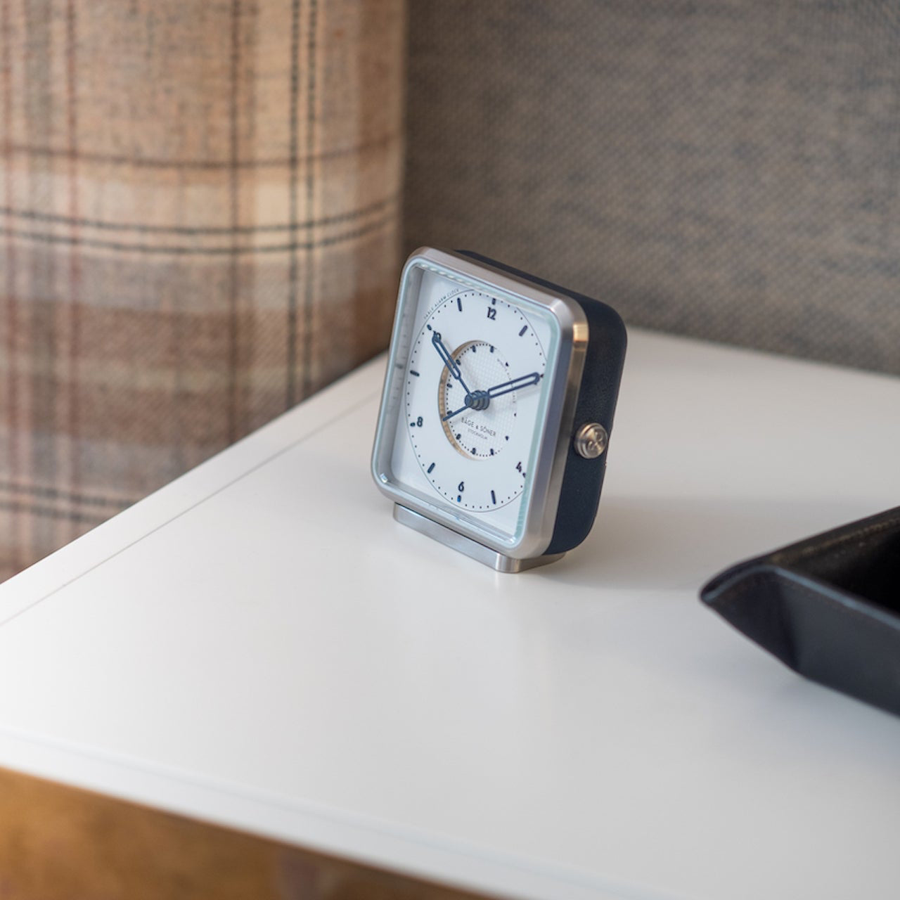 Afternoon Delight' alarm clock on a bedside table, the white dial and blue leather blending tradition and style in decor