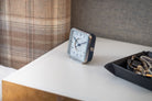 Afternoon Delight' alarm clock on a bedside table, the white dial and blue leather blending tradition and style in decor