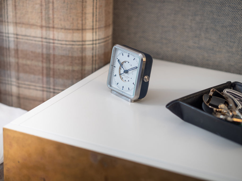 Afternoon Delight' alarm clock on a bedside table, the white dial and blue leather blending tradition and style in decor