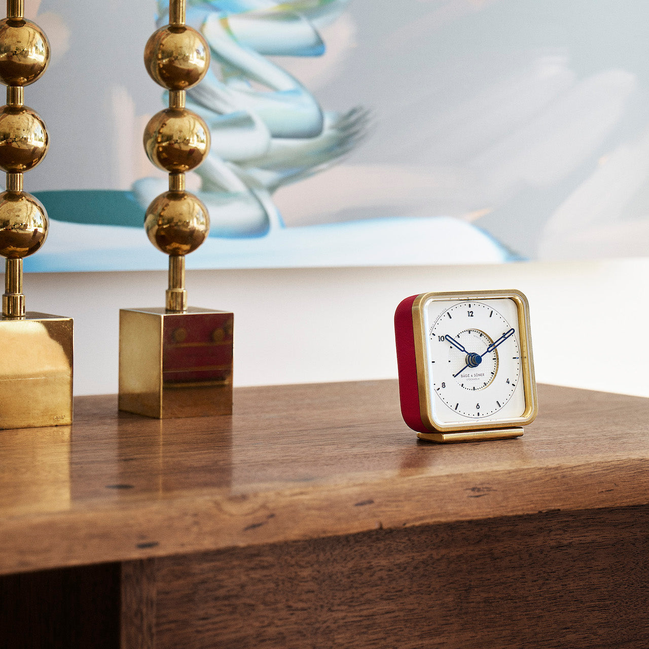 French Kiss' alarm clock on a nightstand, white dial contrasting beautifully with red leather