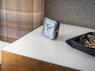 Afternoon Delight' alarm clock on a bedside table, the white dial and blue leather blending tradition and style in decor