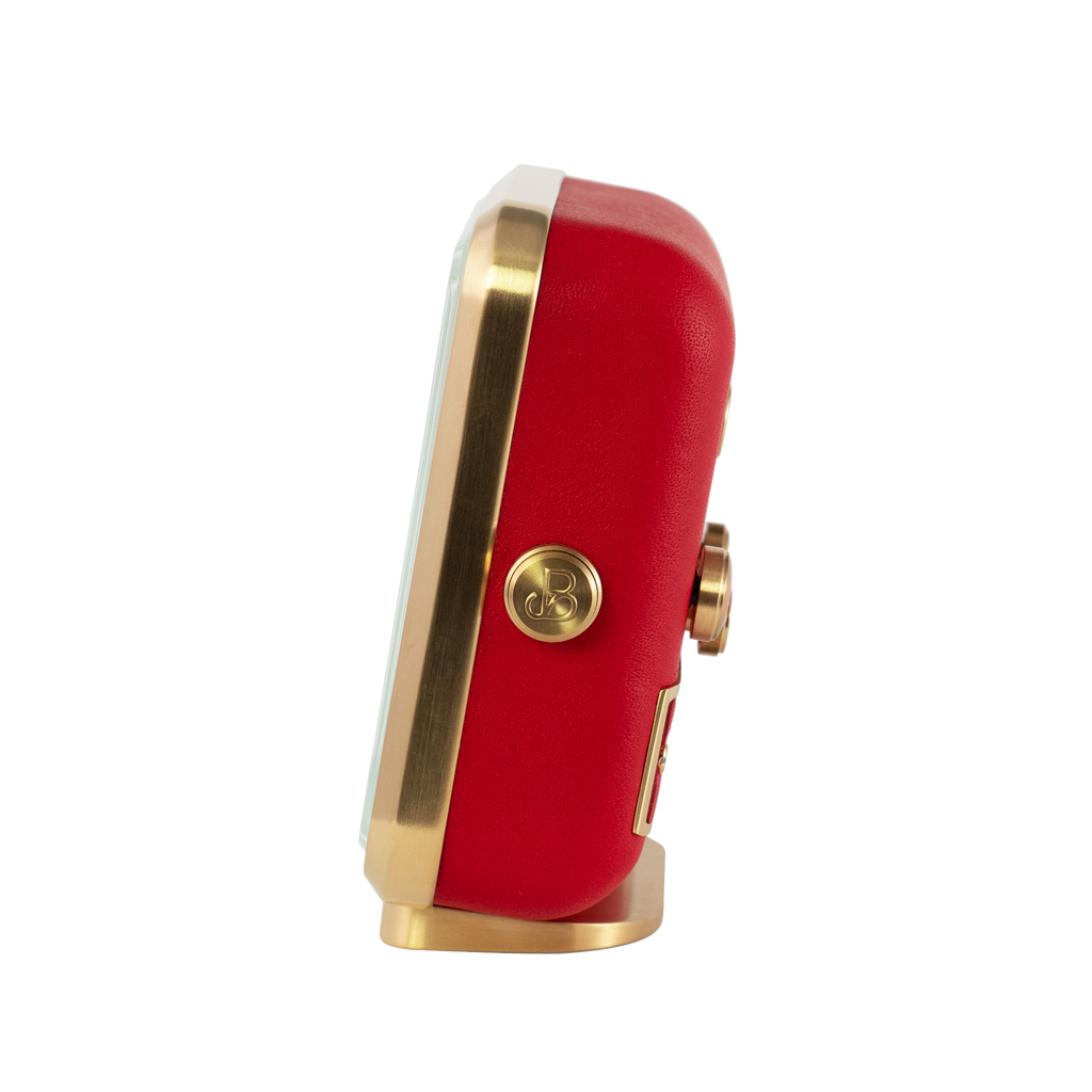 Gold-plated frame and rich red leather captured from the side of 'French Kiss' alarm clock
