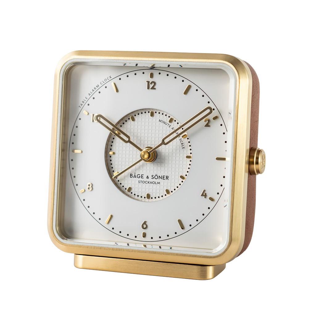 White dial and gold-colored numbers on 'Happy Yawn' alarm clock, with a tappisserie-designed zone and brushed gold-plated stainless steel frame