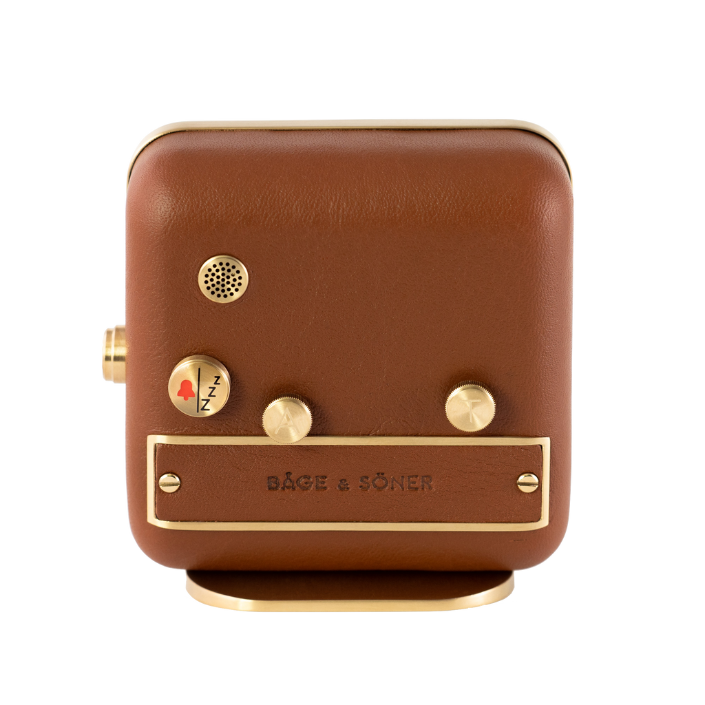 Backside of 'Happy Yawn' alarm clock, revealing the brushed gold-plated finish and cognac leather craftsmanship