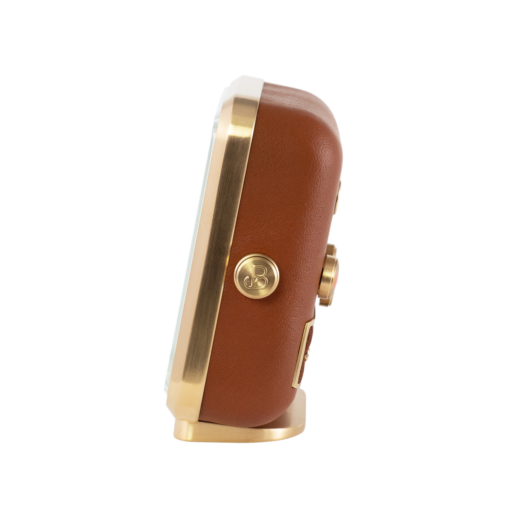 Lateral view of 'Happy Yawn' alarm clock, displaying the fine gold-plated casing and cognac brown leather