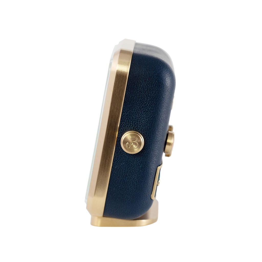 Side perspective of 'Sea Breeze' alarm clock, exhibiting brushed gold plating and elegant blue leather